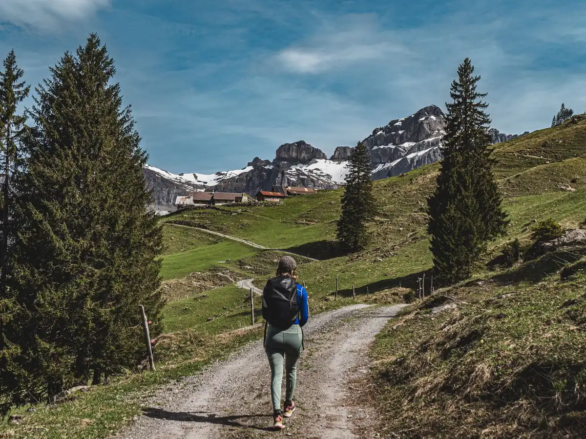 Mujer sola caminando por un sendero de montaña al amanecer con mochila