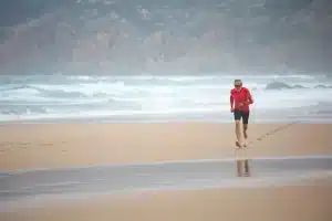 Deportista corriendo en la arena mojada de la playa durante un entrenamiento de velocidad