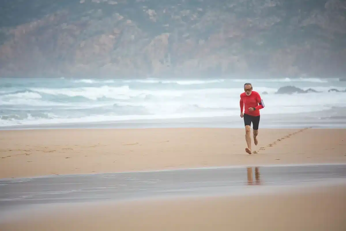 Deportista corriendo en la arena mojada de la playa durante un entrenamiento de velocidad