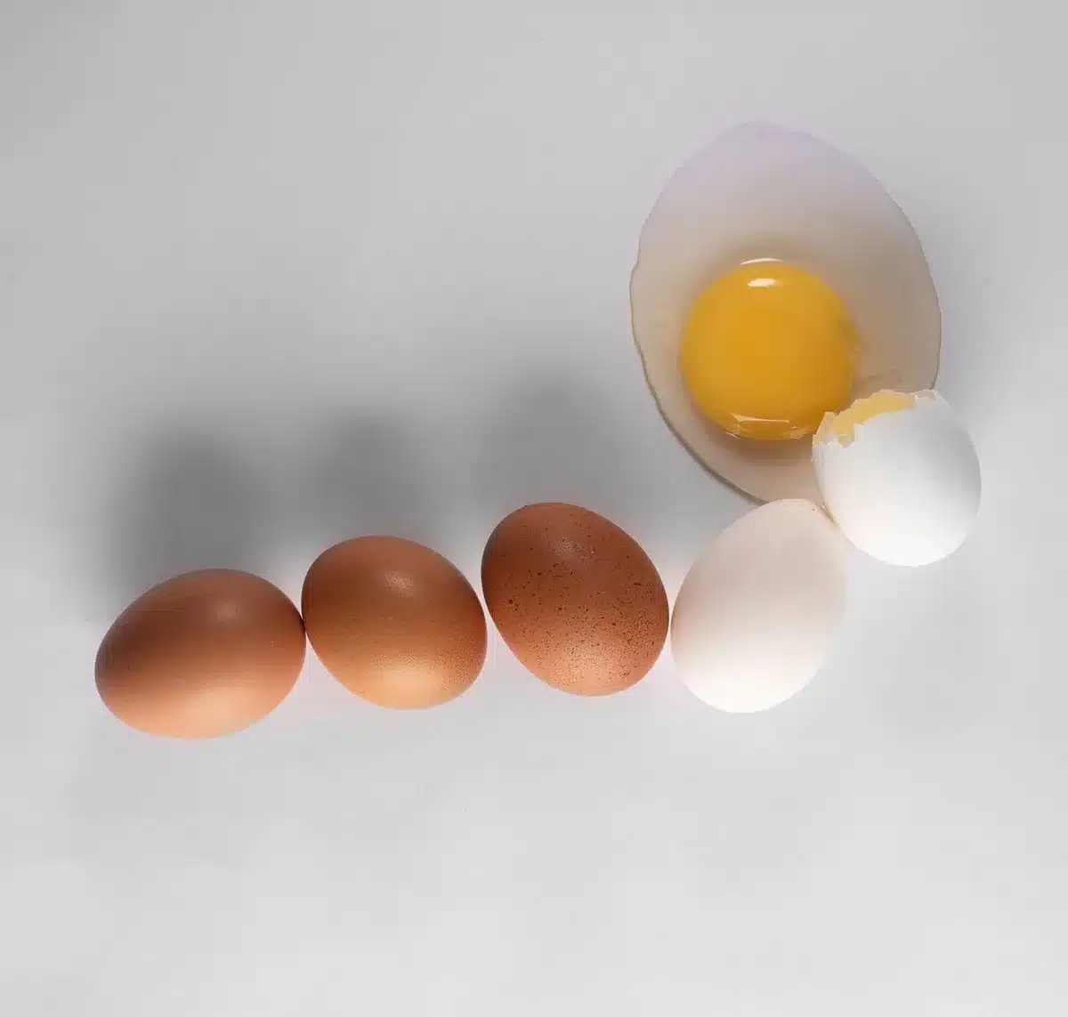 Huevos crudos y cocidos mostrando su valor nutricional en una mesa
