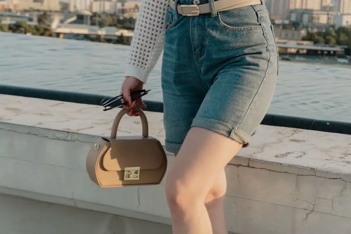 Mujer luciendo un look de verano con bermudas largas, camisa ligera y sandalias