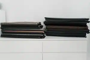 Pila de bermudas largas dobladas en tonos beige, blanco y azul marino sobre una superficie clara