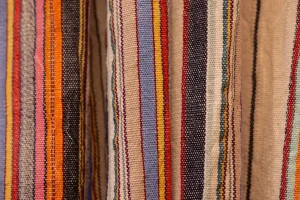 Pantalones de rayas en colores pastel y vibrantes doblados sobre una superficie neutra