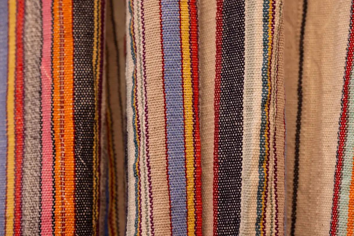 Pantalones de rayas en colores pastel y vibrantes doblados sobre una superficie neutra