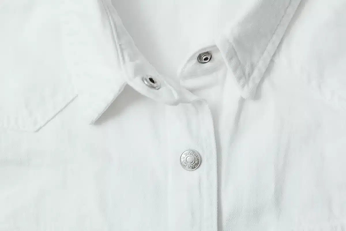 Camisa blanca cruzada sobre fondo neutro mostrando el cierre y la calidad del tejido