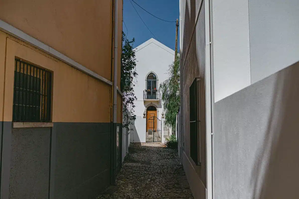 Callejuela estrecha con contraste de luz y sombra entre fachadas blancas