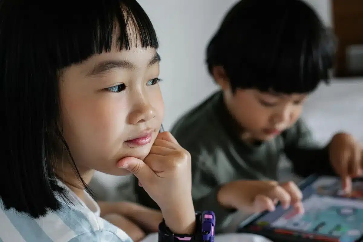 Niño jugando con una tablet mientras juguetes clásicos permanecen abandonados en el fondo.
