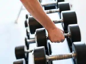 Persona entrenando boxeo en un gimnasio moderno con bolsas de boxeo y luces de estudio