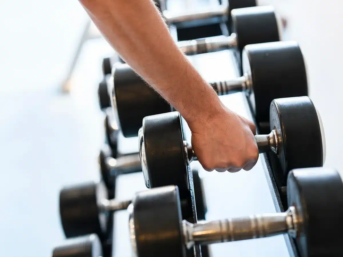 Persona entrenando boxeo en un gimnasio moderno con bolsas de boxeo y luces de estudio