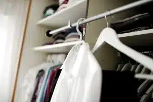 Mujer ajustándose una americana entallada en un probador luminoso, preparándose para la nueva temporada