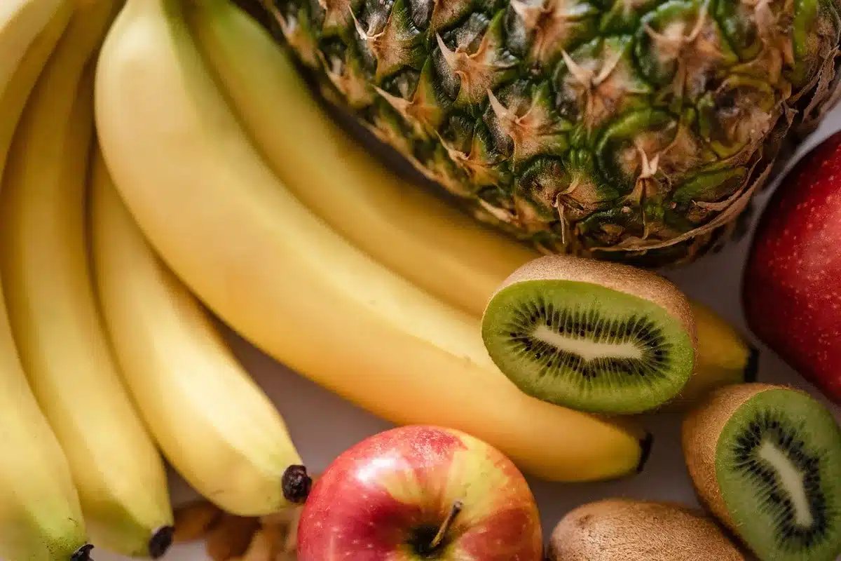 Mano anónima eligiendo entre refresco light y fruta fresca en una cocina