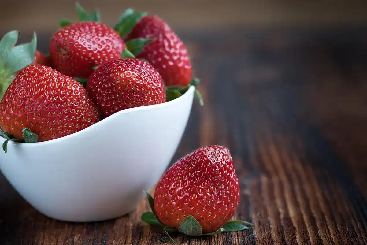 Influencer anónimo sosteniendo un bowl de frutas frente a un teléfono para redes