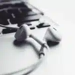Auriculares inalámbricos compactos junto a un estuche alargado sobre una mesa