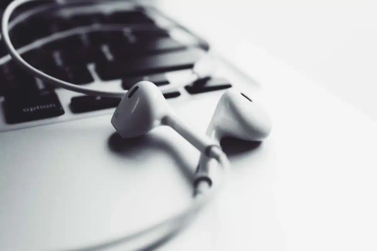 Auriculares inalámbricos compactos junto a un estuche alargado sobre una mesa