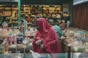 Manos sosteniendo prendas de otoño dobladas en colores neutros durante compras en rebajas.