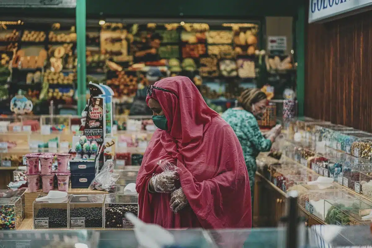 Manos sosteniendo prendas de otoño dobladas en colores neutros durante compras en rebajas.
