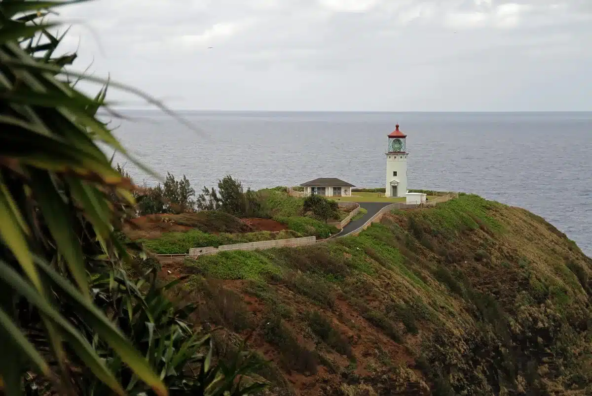 Acantilados con cala turquesa y un faro al fondo vistos desde el sendero
