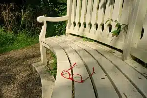Par de zapatos rojos sobre un banco de madera junto a prendas neutras