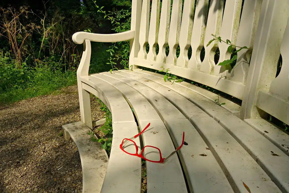 Par de zapatos rojos sobre un banco de madera junto a prendas neutras