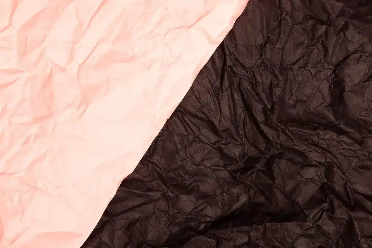 Tela rosa palo y satén iridiscente dobladas para mostrar textura y brillo