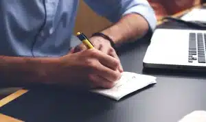 Manos anónimas con cuadernillo de programa y notas en una mesa de hospital