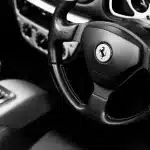 Interior de coche con teléfono en modo CarPlay y manos en el volante