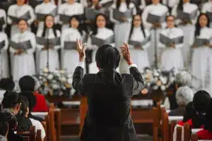 Manos anónimas con smartphones en una sala de concierto, orquesta desenfocada al fondo