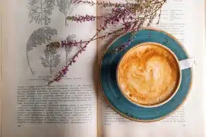 Manos con taza de café junto a prendas de otoño colgadas en un perchero