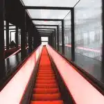 Pasarela semicircular iluminada con estructuras geométricas y telas translúcidas