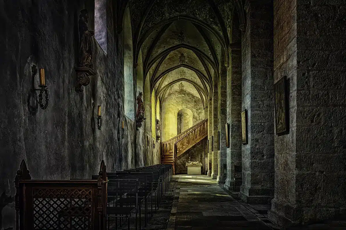 Interior de una iglesia antigua con velas encendidas en penumbra
