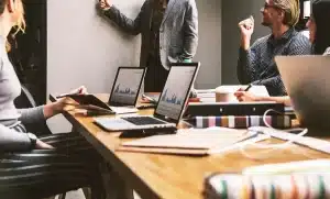 Manos anónimas con carpetas y portátil en mesa de trabajo clínico