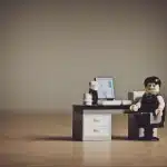 Manos anónimas con figuras de luchadores y una maqueta de arcade sobre una mesa