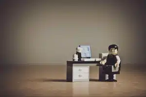 Manos anónimas con figuras de luchadores y una maqueta de arcade sobre una mesa