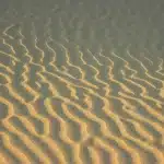 Vista desértica amplia con dunas, dos figuras anónimas y cielo dramático