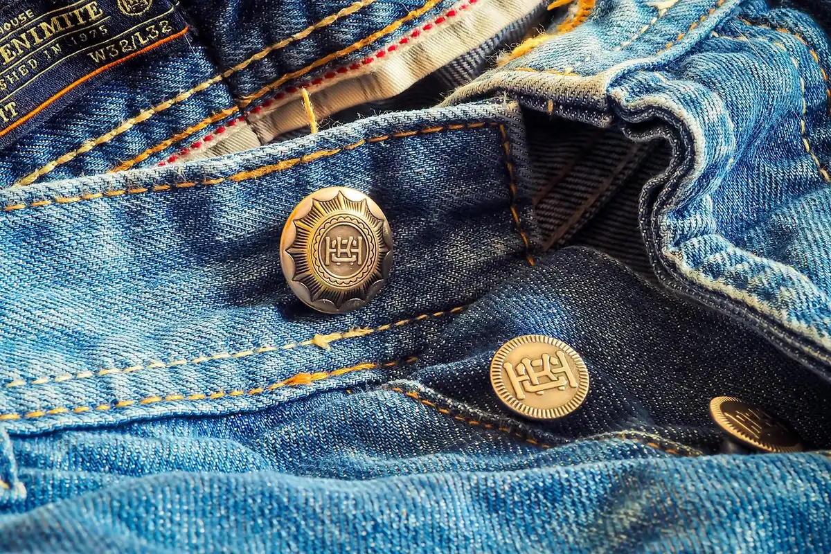 Detalle del bajo vuelto amplio en vaqueros índigo mostrando el contraste interior