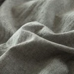 Manos anónimas junto a zapatos de entretiempo y tejidos otoñales sobre una mesa